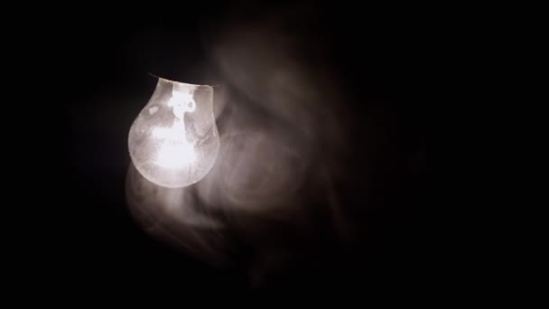 One Hanging Glowing Light Bulb Thick Smoke Black Background Swinging — Stock Video