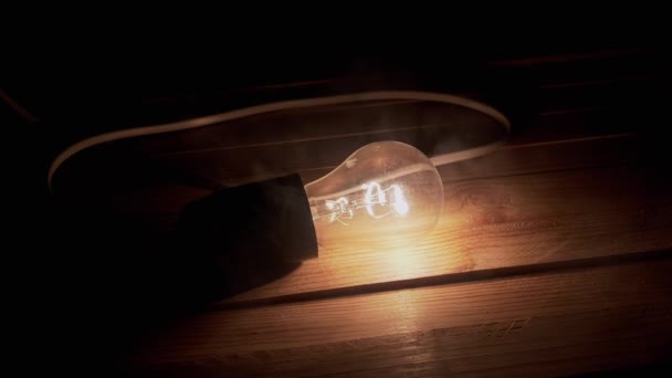 One Glowing Incandescent Light Bulb Wire Lies Wooden Table Smoke — Stock Video