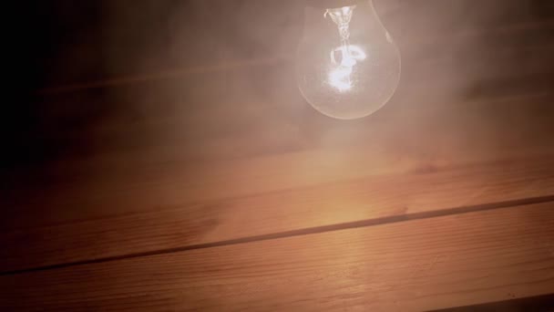 Uma Lâmpada Incandescente Brilhante Balançando Fumo Grosso Fundo Madeira Dusty — Vídeo de Stock