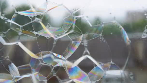 湿淋淋的窗户表面有许多粘稠的彩色肥皂泡 在玻璃表面喷出泡沫的肥皂彩虹泡沫 外面下着雨 — 图库视频影像