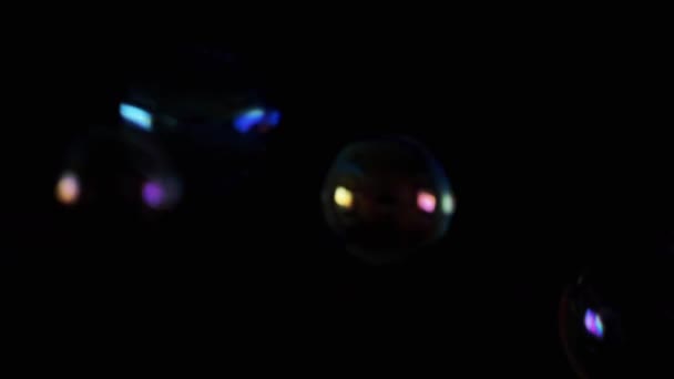 ブラックバックグラウンドで暗闇の中で飛行と落下透明な石鹸の泡 色のついた石鹸の泡の多くは 空っぽの空間で動いています テクスチャー ブレイクされた動き 選択的な焦点 — ストック動画