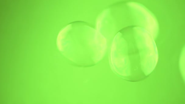 在空旷的空间中绿色背景上的小肥皂泡群漂浮 靠近点吹透明的彩虹水球 模糊的运动 集中注意力 孤立无援铬键 慢动作 — 图库视频影像