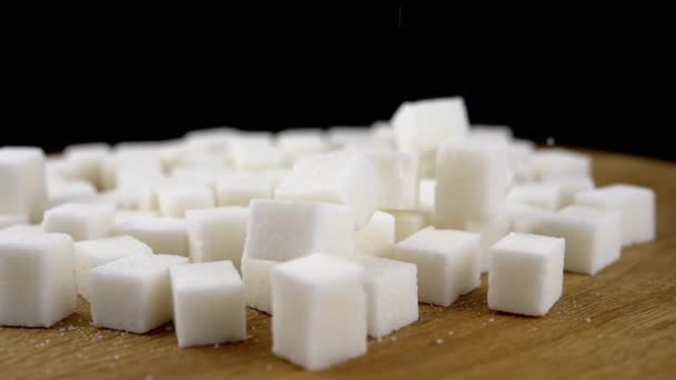 Weiße Zuckerwürfel Fallen Einen Haufen Zucker Auf Einem Rotierenden Holzhintergrund — Stockvideo