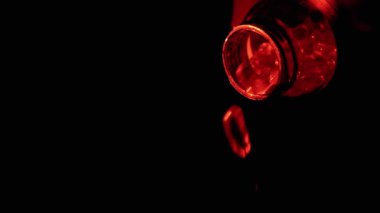 Kırmızı Aydınlatma 'da bir kavanozdan düşen haplar. Saydam haplar, antibiyotikler, fotokopi alanında vitaminler. Soyut, dokusal, arka plan. Tıp, sağlık konsepti.