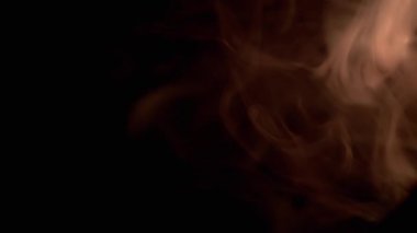 Portakal Dumanı Patlaması ya da Siyah Bulanık Arkaplanda Buhar. Soyut. Yan görüş. Yumuşak dumanlar ya da boş uzayda kaotik bir şekilde buhar karışımı. Parçacık patlaması, parlak ışık. Yavaş çekim.