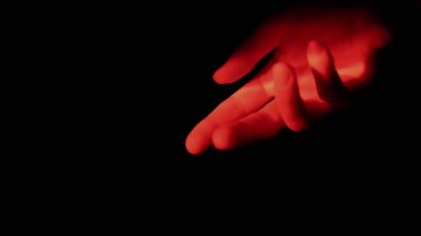 Boşlukta Kara Arkaplanda Kırmızı Aydınlanan El veya Avuç İçi. Parlak neon ışığı verin. Tanımlanamayan kişi, vücut parçası. Jestler. Soyut. Ağır çekim. Kapatın. Bulanık hareket.