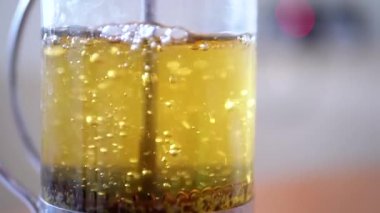 Yakın plan Papatya Çiçeği Çaydanlığındaki Bitki Çayı. Gri, bulanık arka plan. Fransız basınında çay demleme işlemi var. Papatya tomurcukları yüzer ve yükselir. Soyutlama, doku. Makro.