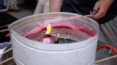 Satıcı, Pamuk Şeker Yapıyor, Sokaklarda Pamuk Şeker Yapan Bir Makine. Konteynırda yanan yakıcı şeker eritir. Çocuklar için bir parti. Sokak şekerleri satıyorum. Kapatın. Yavaş çekim.