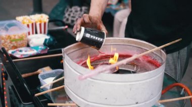 Satıcı Pamuk Şeker Yapıyor, Sokaklarda Pamuk Şeker Yapan Makine. Elleri, şekeri eriten yanan bir yakıcıyla bir kaba şeker döker. Çocuklar için bir parti. Sokak şekerleri. Kapat..