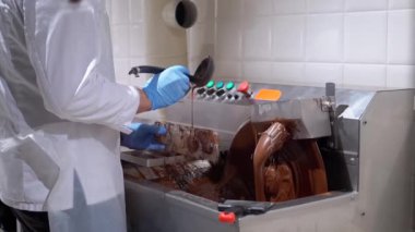 Şekerleme kalıplarına bir şeker kalıbı tarafından sıvı çikolata dökülüyor. Çikolata üretim süreci. Lezzetli tatlılar yaratmak.