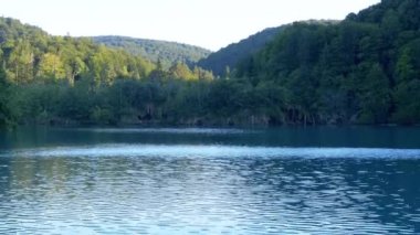 Hırvatistan 'daki Plitvice Gölleri Ulusal Parkı' nın çevresindeki bereketli orman ve tepeleri yansıtan sakin sular, dokunulmamış doğanın huzur dolu güzelliğini gözler önüne seriyor. Bu çarpıcı manzara huzur ve sükuneti temsil ediyor.