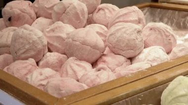 Ahşap bir kutuda sunulan toz şekere bulanmış bir yığın pembe marşmelov. Bu yumuşak, havadar şekerleme, pastane, tatlı ya da sıcak temalı projeler için uygun hassas ve tatlı bir görsel yaratıyor.