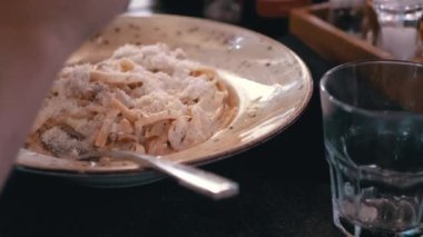 Kremalı makarna tabağı cömertçe rendelenmiş peynir serpiştirilir. Bu davet sahnesi yemek videoları, restoran promosyonları ya da yemek pişirme dersleri için mükemmel..