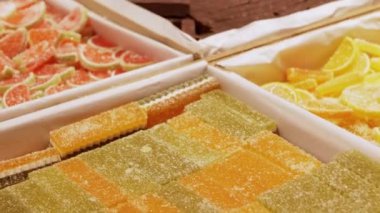 Üzerinde şeker serpiştirilmiş renkli marmelat parçaları, turunçgil dilimleri ve dikdörtgen çubuklara benzer. Bu tatlı ikram çeşitli şekilleri ve canlı renkleri göstererek, görsel olarak