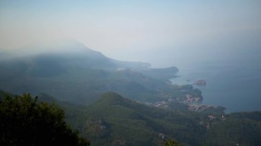 Karadağ kıyılarının sisli bir dağ zeminiyle atmosfer manzarası. yemyeşil tepeler masmavi denize doğru iniyor, mistik bir kıyı manzarası yaratıyor..