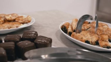 Büfe masasında ıspanaklı pastalar ve çikolatalı kekler servis edilmeye hazır. Yemek, yemek ve konukseverlikle ilgili projeler için mükemmel..