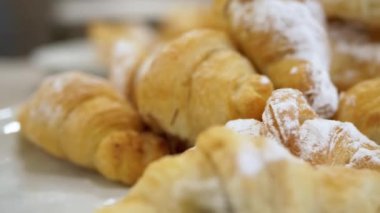 Üzerine pudra şekeri serpiştirilmiş lezzetli altın kruvasanlar serpiştirilip cazip bir tatlı hamur işi sergilenecek. Yemek blogları, fırın reklamları ya da kahvaltı temalı projeler için mükemmel..