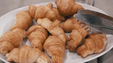 Altın-kahverengi kruvasanlar beyaz bir tabakta üst üste yığılmış, keyif almaya hazır. Kahvaltı, brunch ya da öğle yemeği için mükemmel..