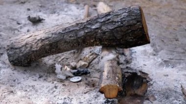 Kamp ateşinin küllerinde yanmış kütükler ve çöpler. Bu görüntüler insan aktivitesinin doğa üzerindeki olumsuz etkisini ve sorumlu kampın önemini gösteriyor..