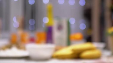 Noel yemeği masasının bulanık görüntüsü, şenlikli dekorasyon, yiyecek ve içeceklerle sıcak bir tatil ortamı yaratıyor. Odak dışı çekim, kutlama beklentisini vurguluyor.