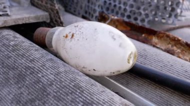 Tozlu, ıskartaya çıkmış bir ampul, atık ve çevresel bozulma temalarını vurgulayarak, diğer enkazların arasında yer alır..