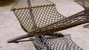 Boş bir hamak kumlu bir plajda nazikçe sallanıyor, rahatlama ve sükuneti davet ediyor. Seyahat, eğlence ya da tatil temalı projeler için mükemmel.