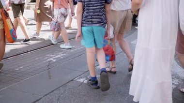 İnsanlar güneşli bir günde şehir caddesi boyunca yürürler. Yürüyen insanların bacakları. Turizm ve eğlence kavramı..