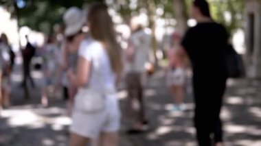 Bulanık bir grup insan ağaçların arasından süzülen benekli güneş ışığıyla bir şehir parkında yürüyor. Kentsel yaşam, seyahat ve boş zamanlarla ilgili projeler için mükemmel bir geçmiş.