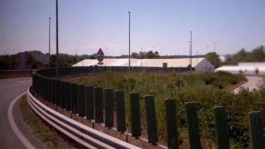 Yol kenarındaki çadır ve yapılara doğru giden bir otoyol kavisi. Trafik akışını gösteren işaretler var. Seyahat, altyapı ve etkinlikle ilgili projeler için uygundur.