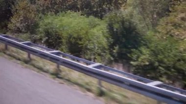 Bir otoban boyunca yemyeşil ağaçlar ve çalılar geçiyor. Hareket halindeki bir araçtan sakin bir görüntü, seyahat ve doğa projeleri için mükemmel..