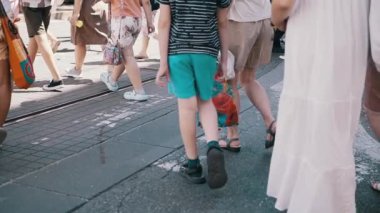 Güneşli bir yaz gününde bir grup insan şehir caddesinde yürür. Yürüyen yayaların bacakları ve ayakları. Yavaş çekim. Seyahat kavramı.