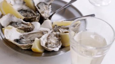 Limon dilimleri ve soğuk beyaz şarapla servis edilen taze, sulu istiridyeler. Zarif ve lezzetli bir aşçılık deneyimi..