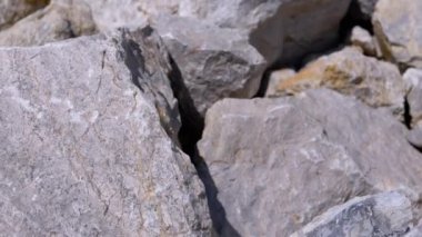 Büyük taş yığınlarına yakın çekim yaparak pürüzlü dokularını ve pürüzlü yüzeylerini sergiliyorlar. Kamera kayaların üzerinde kayarak doğal ve ham bir görüntü oluşturur..
