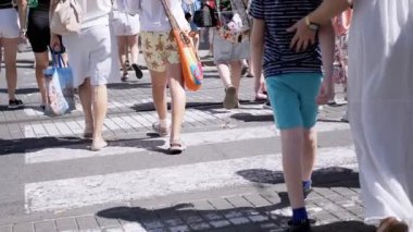 İnsanlar tramvay rayları olan bir caddeyi geçiyor. Yürüyen insanların bacakları. Yaz günü. Ağır çekim. Kentsel yaşam ve seyahat kavramı.