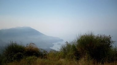 Karadağ kıyılarının manzarası, dağların denizi sisli bir şekilde kucaklamasıyla. Doğal güzelliğin sakin bir sahnesi..