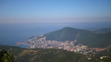 Karadağ 'daki bir dağın zirvesinden Budva' nın resimli manzarası. Kıyı kenti bereketli bitki örtüsüyle çevrili ve huzurlu bir kaçış yolu sunuyor. Balkanların güzelliğini keşfedin.