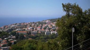 Karadağ 'ın Adriyatik Denizi' ne bakan bir yamaçtaki kıyı kasabasının manzarası. Kırmızı kiremit çatılı evler manzarayı çevreleyen yeşilliklerle harmanlıyor. Mükemmel.