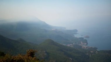 Montenegros kıyı şeridinin manzarası. Çerçevesinde bir tünel ve hız sınırı için uyarı levhası var. Bereketli yeşillik, dağ yamacını renklendiriyor. Resmedilmeye değer manzaraya ekliyor..