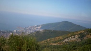 Budva Riviera ve Karadağ kıyı şeridine tepeden bakan manzaralı bir gezinti. Dağlarla, şehirlerle ve okyanuslarla dolu resimli bir manzara. Yaz yolculuğu konsepti.