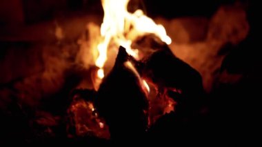 Gece yoğun bir şekilde yanan şenlik ateşinin yakın çekimi, sıcak ve titrek bir parıltı yaratır. Kamp, doğa, sıcaklık ve rahatlama ile ilgili projeler için mükemmel..