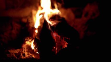 Gece yanan bir kütüğe yakın çekim. Ateşin sıcak parıltısı rahat bir atmosfer yaratır. Kamp, hayatta kalma ya da kış sıcaklığıyla ilgili projeler için mükemmel. Görüntüler aynı zamanda tehlikeyi de sembolize ediyor.