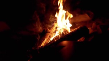 Geceleri büyüleyici bir kamp ateşine yakın çekim, yanan odunların üzerinde dans eden alevler, doğada sıcak ve davetkar bir atmosfer yaratma, kamp, macera ya da doğa projeleri için mükemmel.