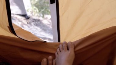Çadırdan çıplak ayaklar sarkıyor, doğada dinleniyor. Kamp, doğada bir sabah, manzaranın tadını çıkarmak..