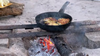 Kamp ateşinin üstünde tavuk pişirmek. Hayatta kalma becerileri, doğada yemek pişirme, kamp yapma ve yürüyüş konsepti. Turist, balıkçı ya da avcı yaşam tarzını somutlaştıran kırsal bir yemek..