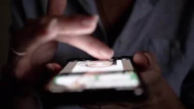 Karanlıkta akıllı telefon kullanan, kaydıran ve tarayan bir kadın. Mobil teknoloji ve sosyal medya ile ilgili projeler için harika.