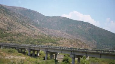 Hırvat dağlarında bir vadi boyunca uzanan beton bir köprü. Bereketli yeşillik ve berrak bir gökyüzü huzurlu bir atmosfer yaratır..