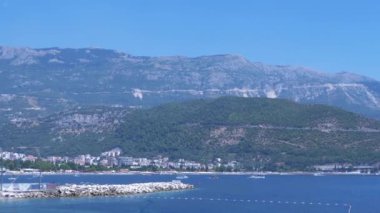 Karadağ 'daki Budva kıyı şeridinin resimli manzarası, oteller, plajlar ve parlak mavi gökyüzü altındaki dağlar..