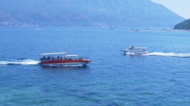 Adriyatik Denizi 'nin gök mavisi sularında iki tur teknesi dolaşırken, Sveti Nikola Adası ve Karadağ kıyıları zemin olarak kullanılıyor. Seyahat ve turizm videoları için ideal bir ortam..