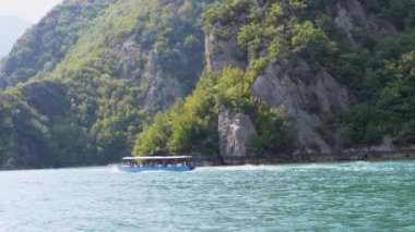 Turistler Arnavutluk 'un Koman Gölü' nde manzaralı bir tekne gezisinin keyfini çıkarıyorlar. Berrak yeşil dağlar ve kristal berraklığında sular cennet gibi bir yaz kaçamağı yaratır..