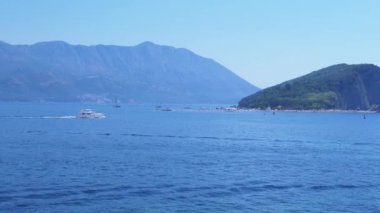 Karadağ 'daki Budva Riviera' nın bir parçası olan Sveti Stefan adası yakınlarındaki masmavi Adriyatik Denizi 'nde parlak beyaz bir yat dolaşıyor.